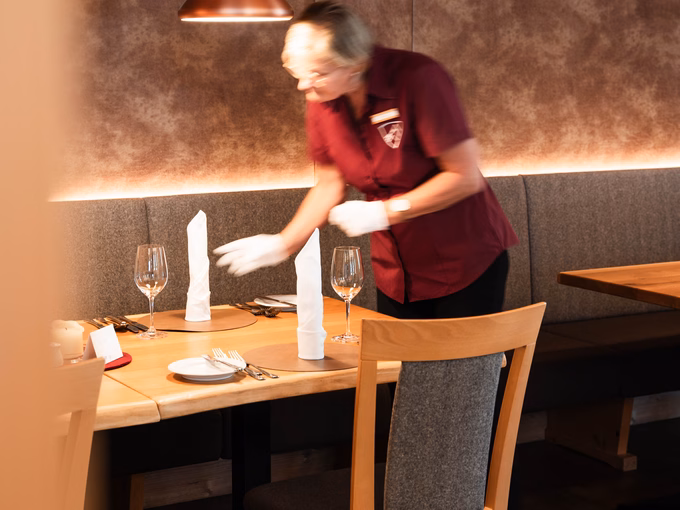 Kellnerin deckt Tisch auf