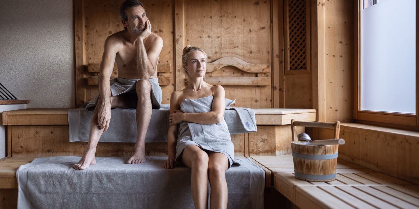 Paar auf unterschiedlichen Ebenen in der finnischen Sauna sitzend im Naturhotel Outside in Matrei in Osttirol