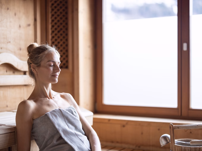 Eine Frau genießt mit geschlossenen Augen die Wärme in der finnischen Sauna im Naturhotel Outside in Matrei in Osttirol
