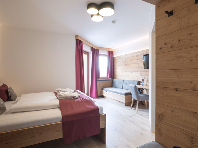 Helles Bergzimmer Plus mit Holzbett, gemütlicher Sitzbank, Schreibtisch und Balkonzugang im Naturhotel Outside in Matrei in Osttirol.