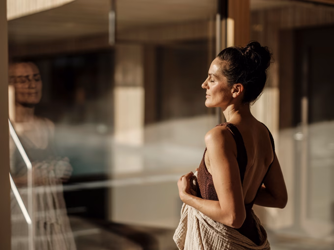 Dame genießt die Sonnenstrahlen am Fenster im Natur SPA