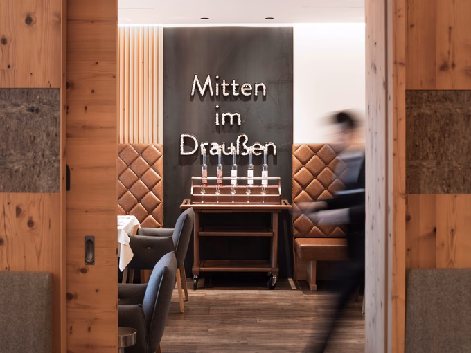 Ein Blick durch ein Holzportal in das Restaurant Inside im Naturhotel Outside während des aktiven Abendservice in Matrei in Osttirol.