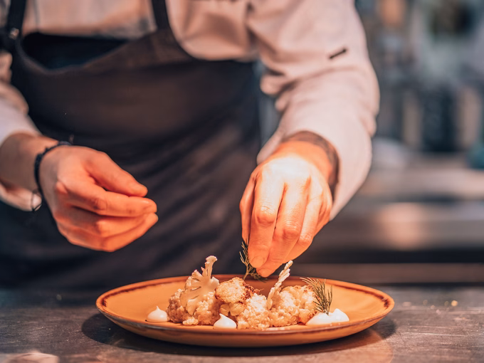 Der Küchenchef verfeinert mit höchster Präzision ein Gericht im Naturhotel Outside in Matrei in Osttirol.