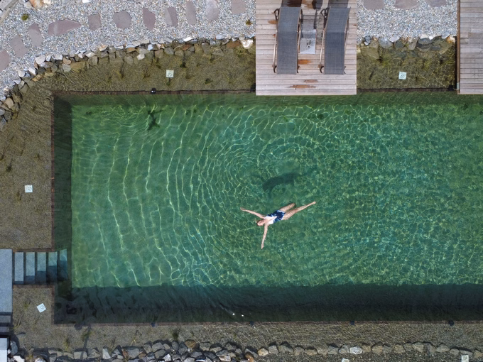 Vogelperspektive auf eine schwimmende Person im chlorfreien Naturpool beim Naturhotel Outside in Matrei in Osttirol