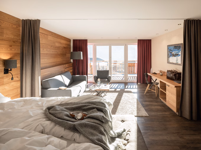 Sonnige Natursuite mit Doppelbett im Vordergrund, Sitzecke und Balkonfront im Naturhotel Outside in Matrei in Osttirol