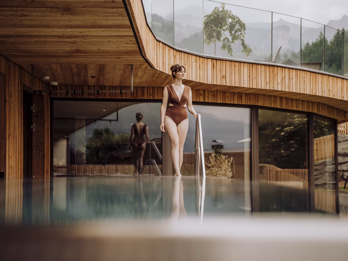 Weite Ansicht des beheizten Pools mit Spiegelung der Berge im Naturhotel Outside in Matrei in Osttirol.