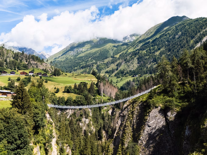 Blick auf die Hängebrücke in Virgen und die umliegenden Almhütten beim Naturhotel Outside in Matrei in Osttirol.