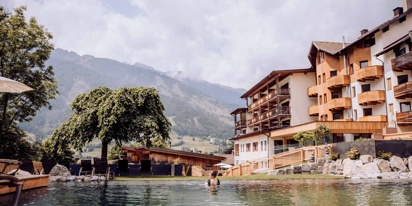 Blick über den Naturpool zum Hotel und die Bergkulisse