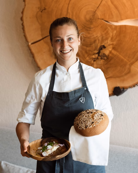 Köchin Verena mit ihrem Graukäse-Brot und einem frischen Laib Brot im Naturhotel Outside in Matrei in Osttirol.