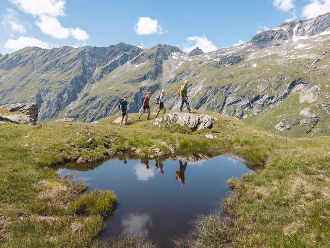 Wanderer laufen an kleinem Bergtümpel vorbei
