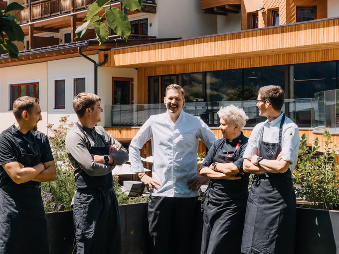 Das gesamte Küchenteam vom Naturhotel Outside in Matrei in Osttirol posiert vor der Bergkulisse.