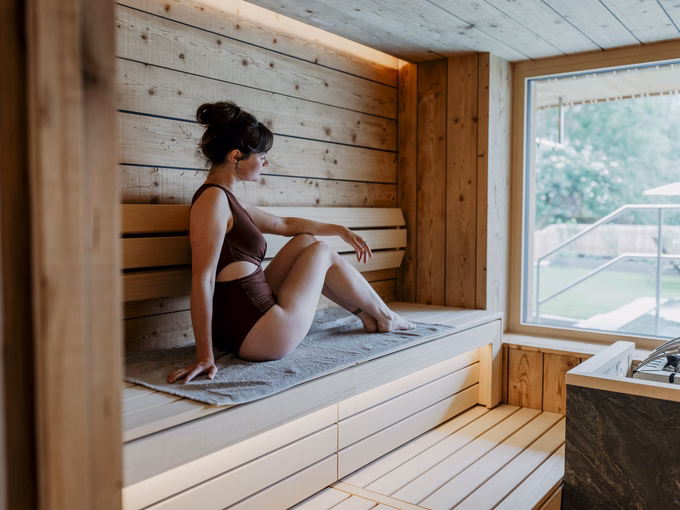 Gast beim Entspannen in der Sauna mit Blick ins Grüne beim Naturhotel Outside in Matrei in Osttirol.