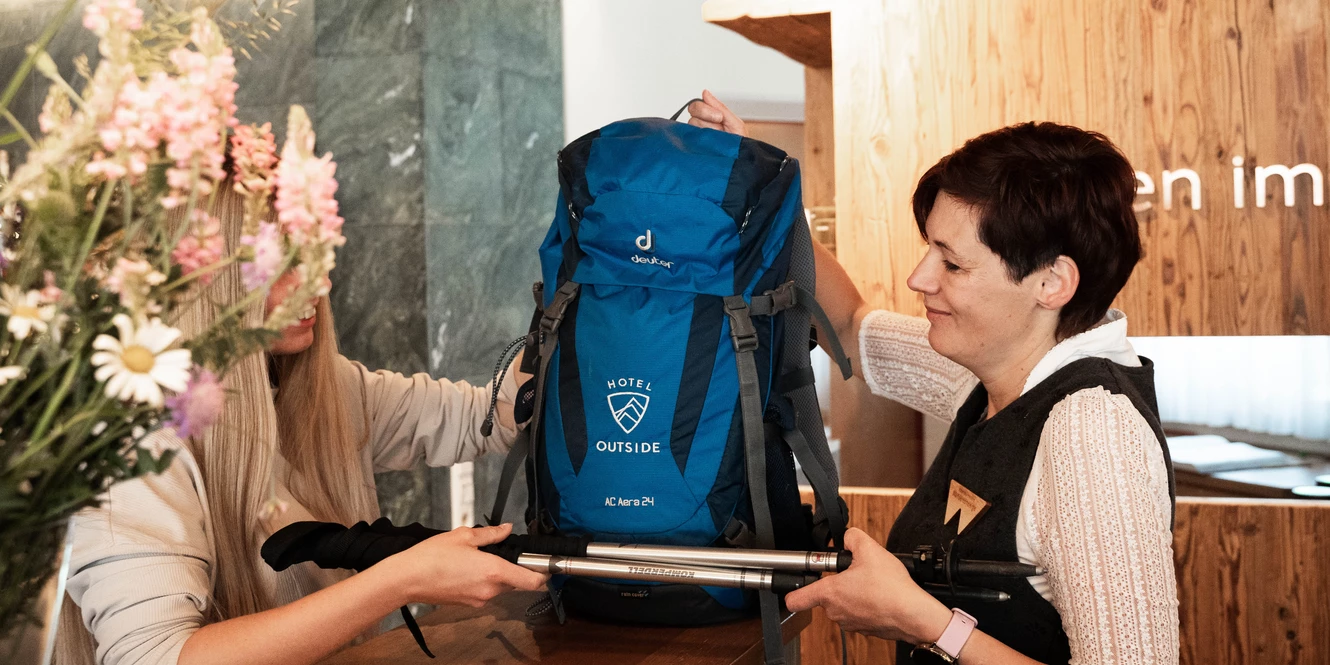 Karin übergibt Gast das Wanderequipment