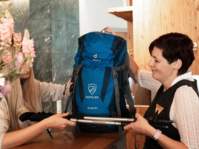 Karin übergibt Gast das Wanderequipment