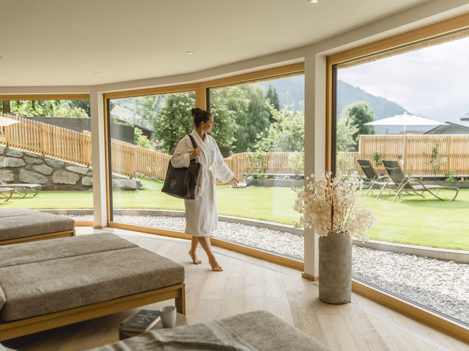 Frau im Bademantel spaziert durch den lichtdurchfluteten Wellnessbereich beim Naturhotel Outside in Matrei in Osttirol.