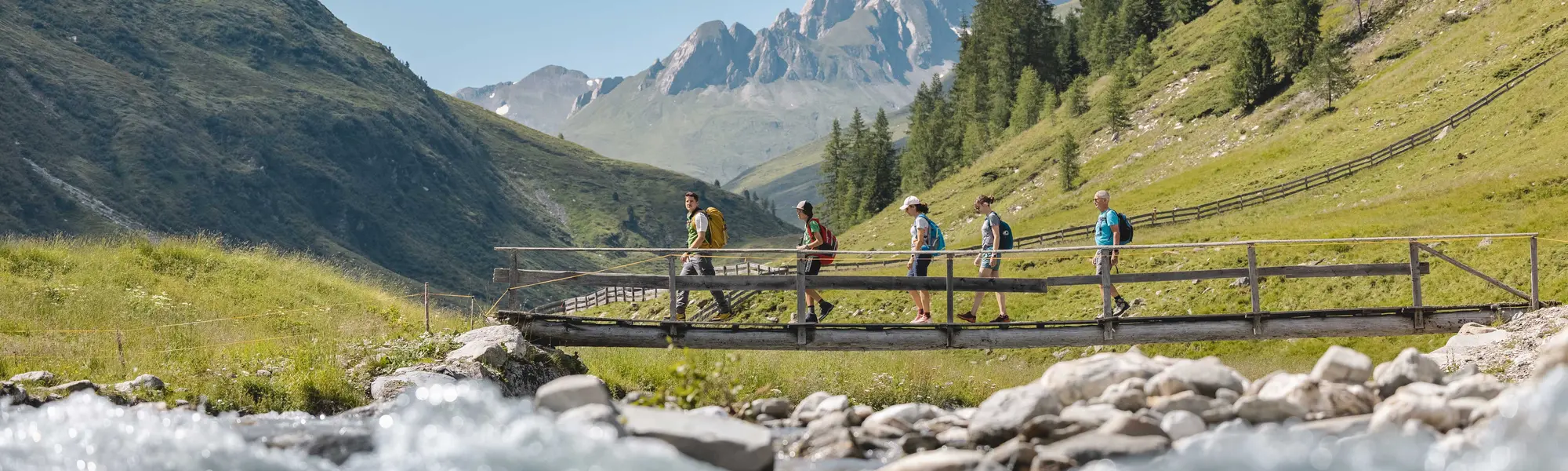 Wanderer queren kleine Brücke über Gebirgsbach