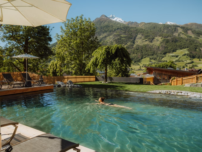 Schwimmende Frau im weitläufigen Naturbadeteich mit Blick auf die Berggipfel im Naturhotel Outside in Matrei in Osttirol