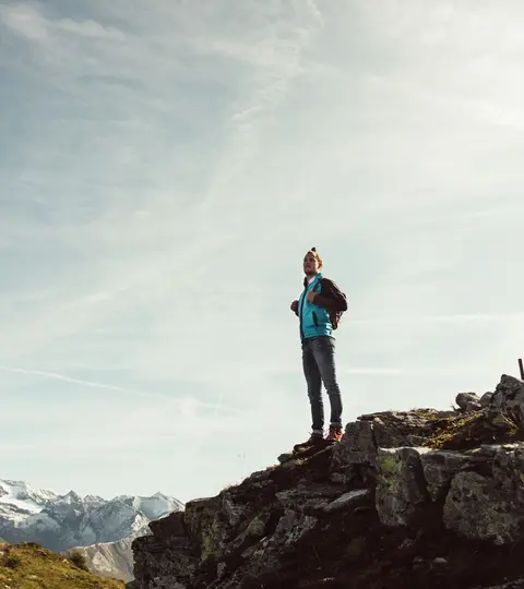 Wanderer steht auf Berggipfel in Osttirol mit Blick auf den Großglockner.