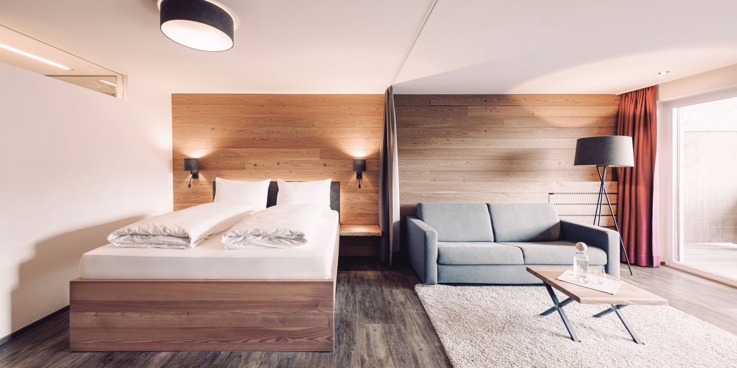 Helle Natursuite mit Doppelbett aus Holz, Sitzecke und Holzwand im Naturhotel Outside in Matrei in Osttirol