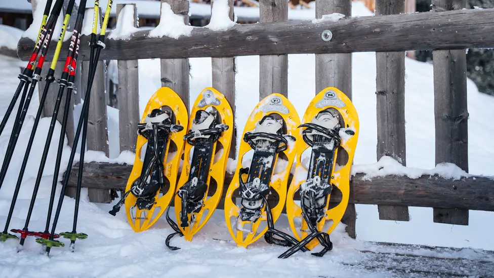 Gelbe Schneeschuhe lehnen an Zaun