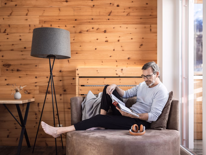 Mann liegt am Sofa und liest Zeitschrift