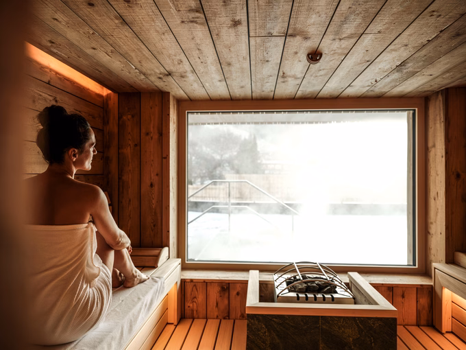Frau in der Bio-Sauna mit Panoramafenster und Blick nach draußen im Naturhotel Outside in Matrei in Osttirol
