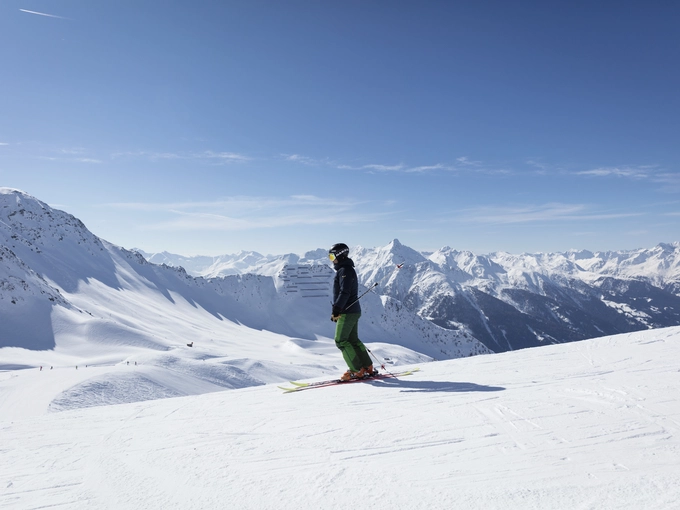 Skifahrer fährt bei tollem Schnee und blauem Himmel talwärts