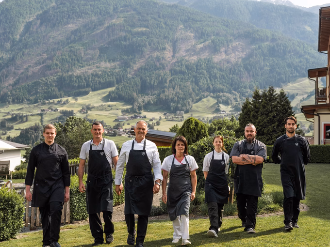 Das gesamte Küchenteam vom Naturhotel Outside in Matrei in Osttirol posiert vor der Bergkulisse.