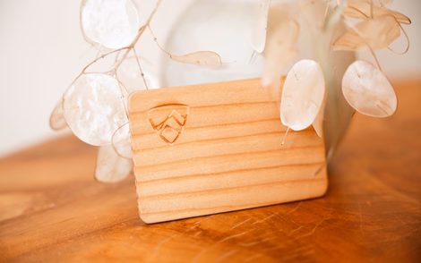 Detailaufnahme einer hölzernen Schlüsselkarte mit Logo-Gravur auf einem Holztisch im Naturhotel Outside in Matrei in Osttirol