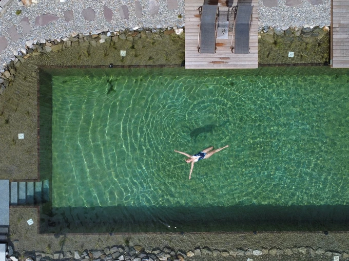 Sicht von oben auf Frau die im Naturpool schwimmt