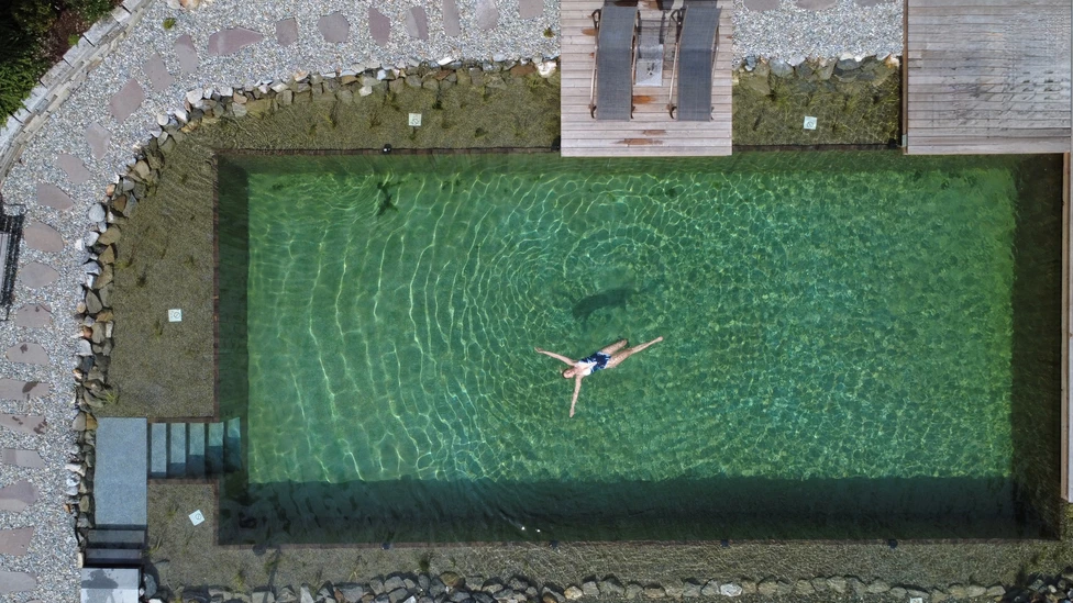 Sicht von oben auf Frau die im Naturpool schwimmt