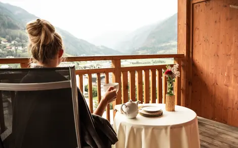 Frau genießt den Ausblick vom Balkon bei einer Tasse Tee